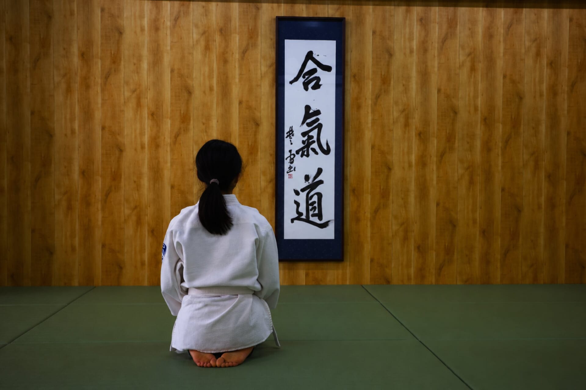 合氣道の掛け軸の前で正座する道場生
